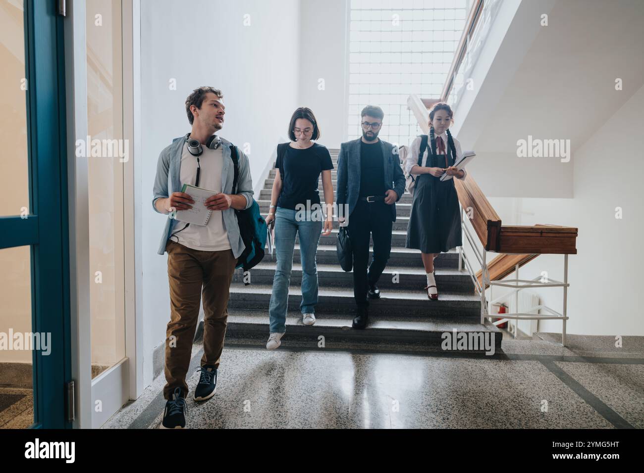 Group of students with professor walking down the school staircase ...