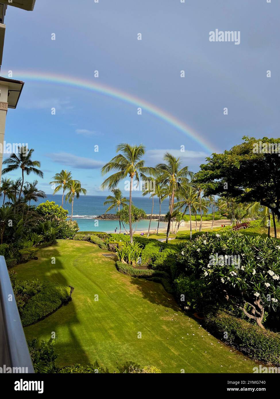 A stunning view from a clifftop overlooking a secluded cove with a sandy beach and crystal clear turquoise water. People are enjoying the beach - Smartphone Captured Stock Image
