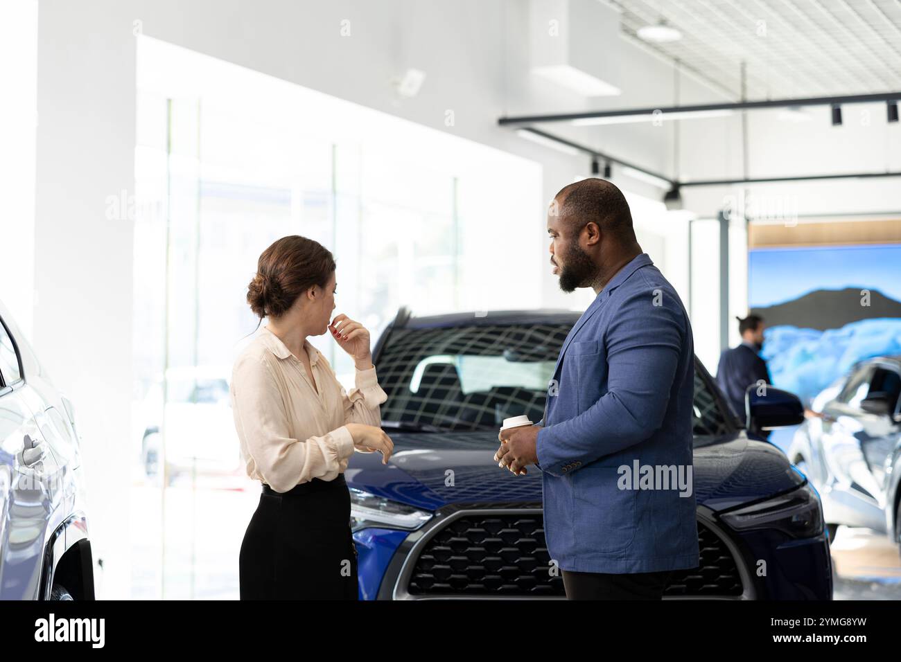 Customers in car dealership browsing through available models, trying