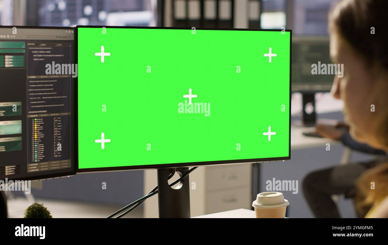 Computer scientist working, doing software debugging using mockup PC, troubleshooting errors. Woman in office fixing coding issues using green screen computer, solving tasks, camera A Stock Photo