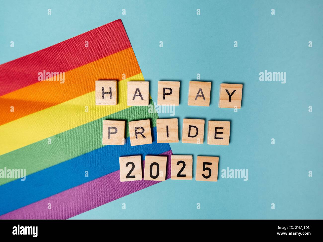 Rainbow is on a blue background with the words Happy Pride 2025 written in wooden blocks. The rainbow and the blocks create a playful and colorful atm Stock Photo