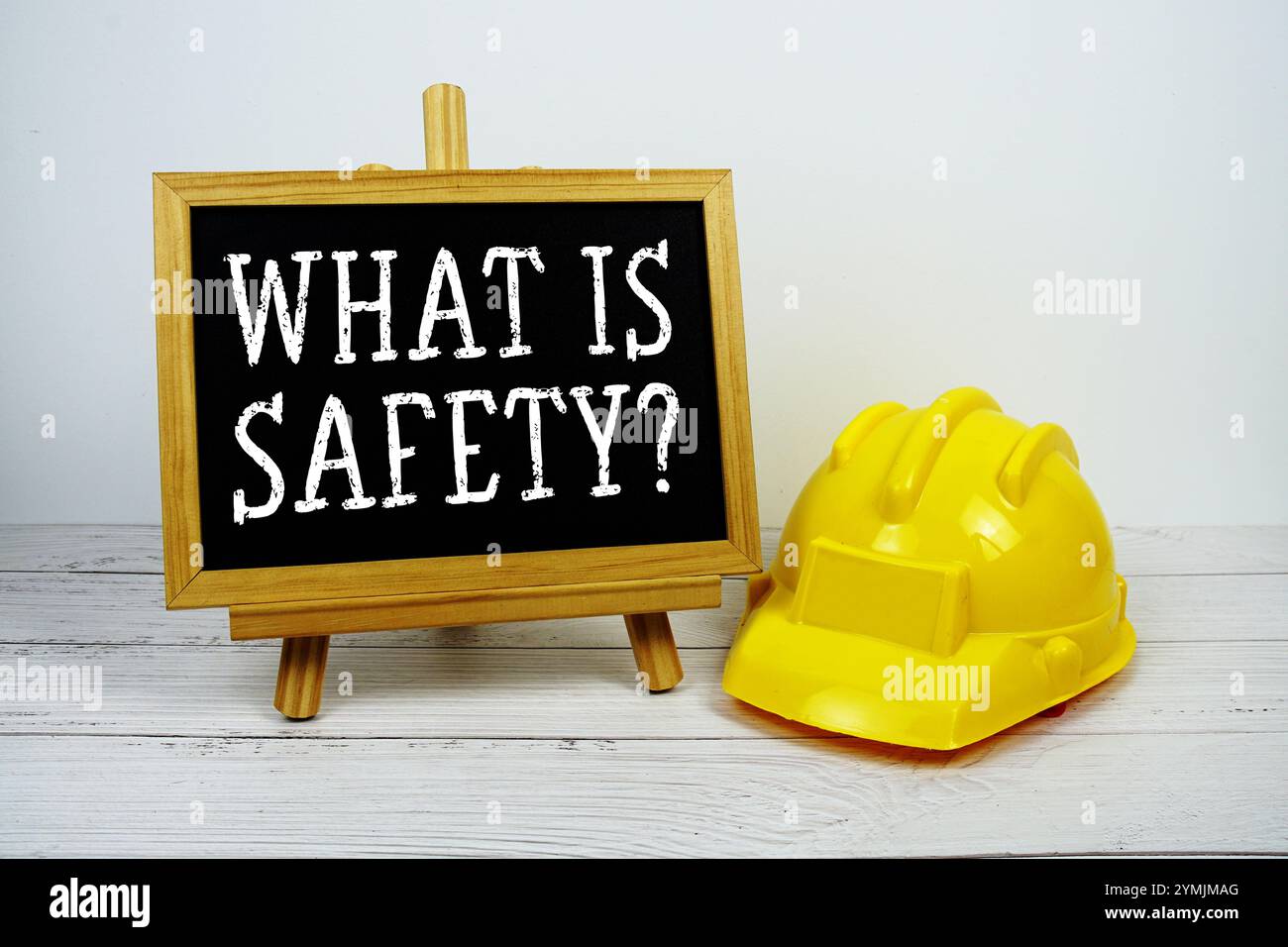 What Is Safety? text on blackboard with safety helmet on wooden background Stock Photo