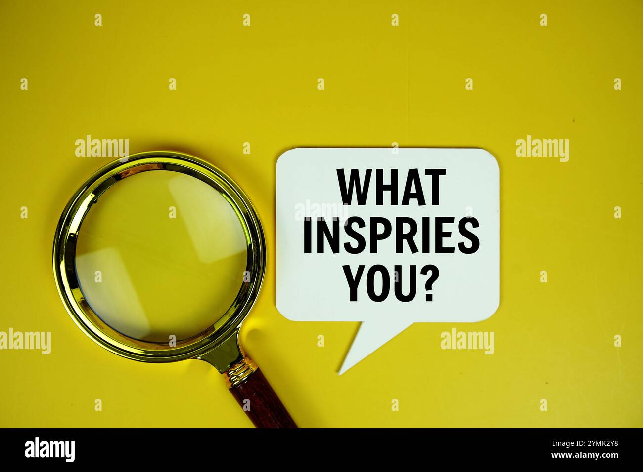 What inspries you? text on speech bluble with magnifying glass top view on yellow background Stock Photo