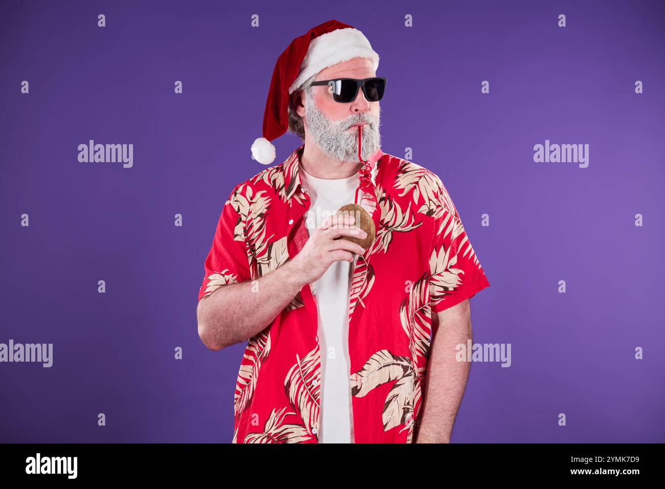 Man wearing Santa hat and sunglasses drinking from a bottle against a ...