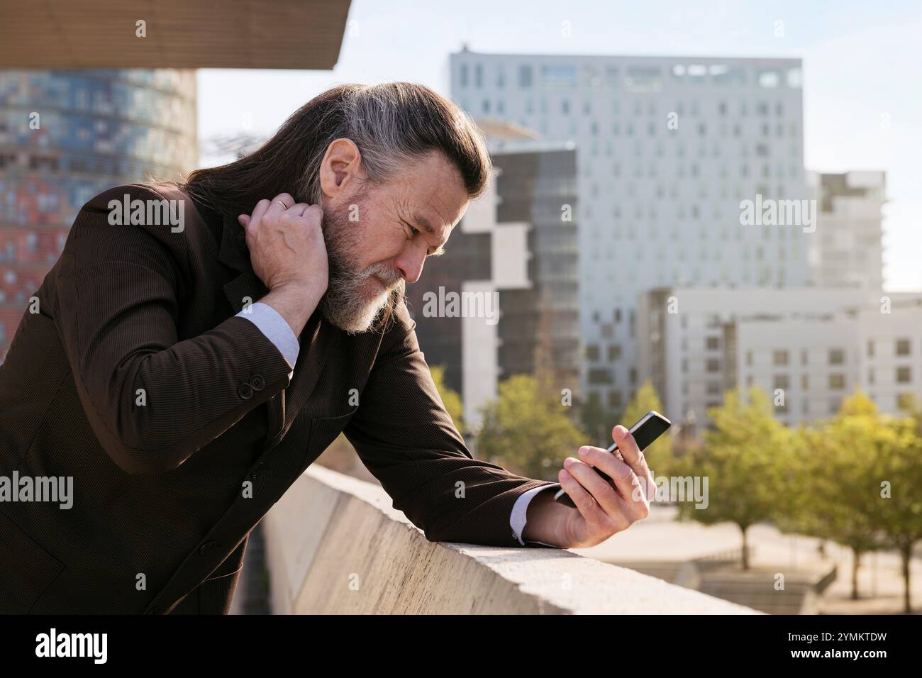 concerned mature man in suit using mobile phone Stock Photo