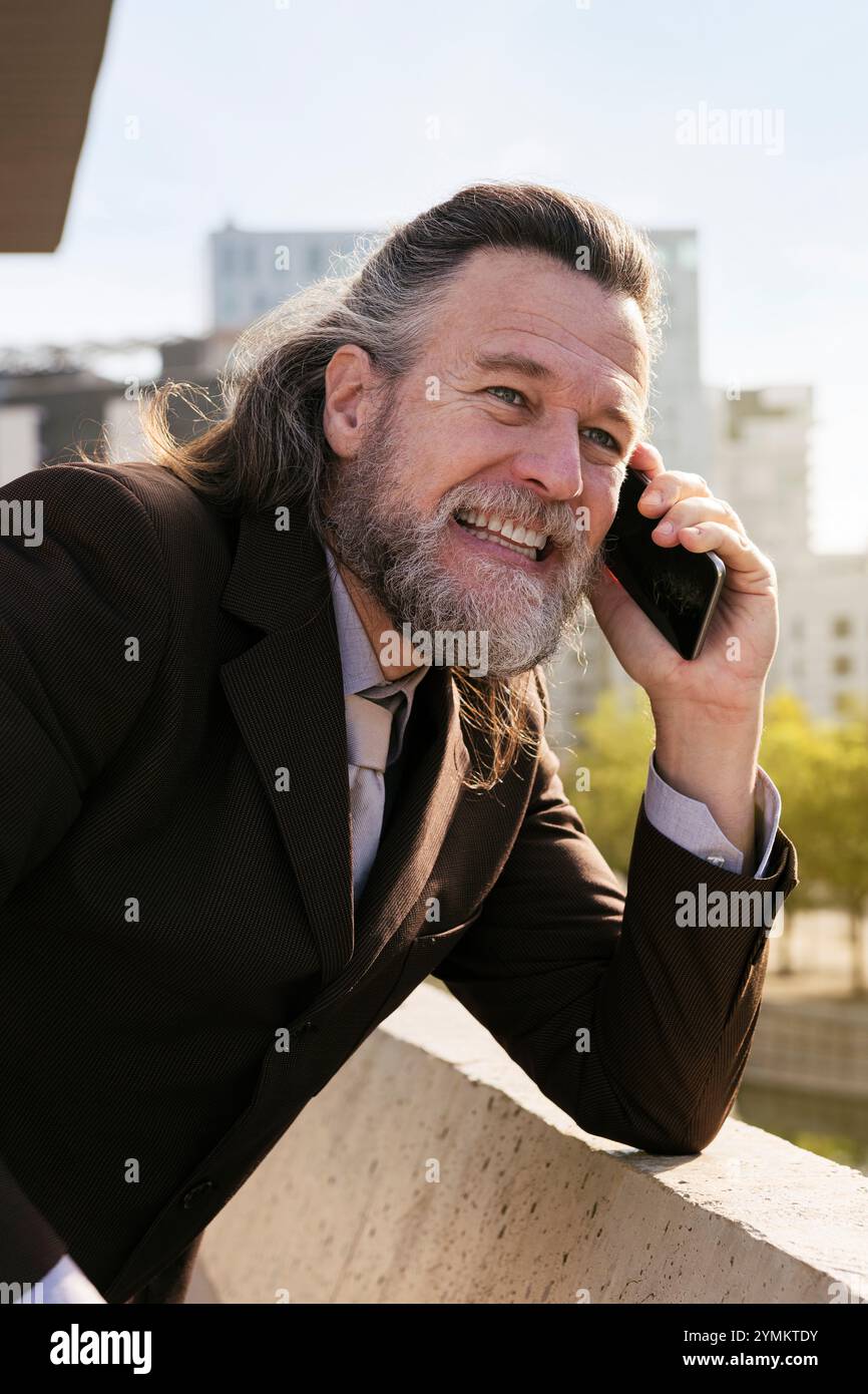 smiling middle age man with beard talking on phone Stock Photo