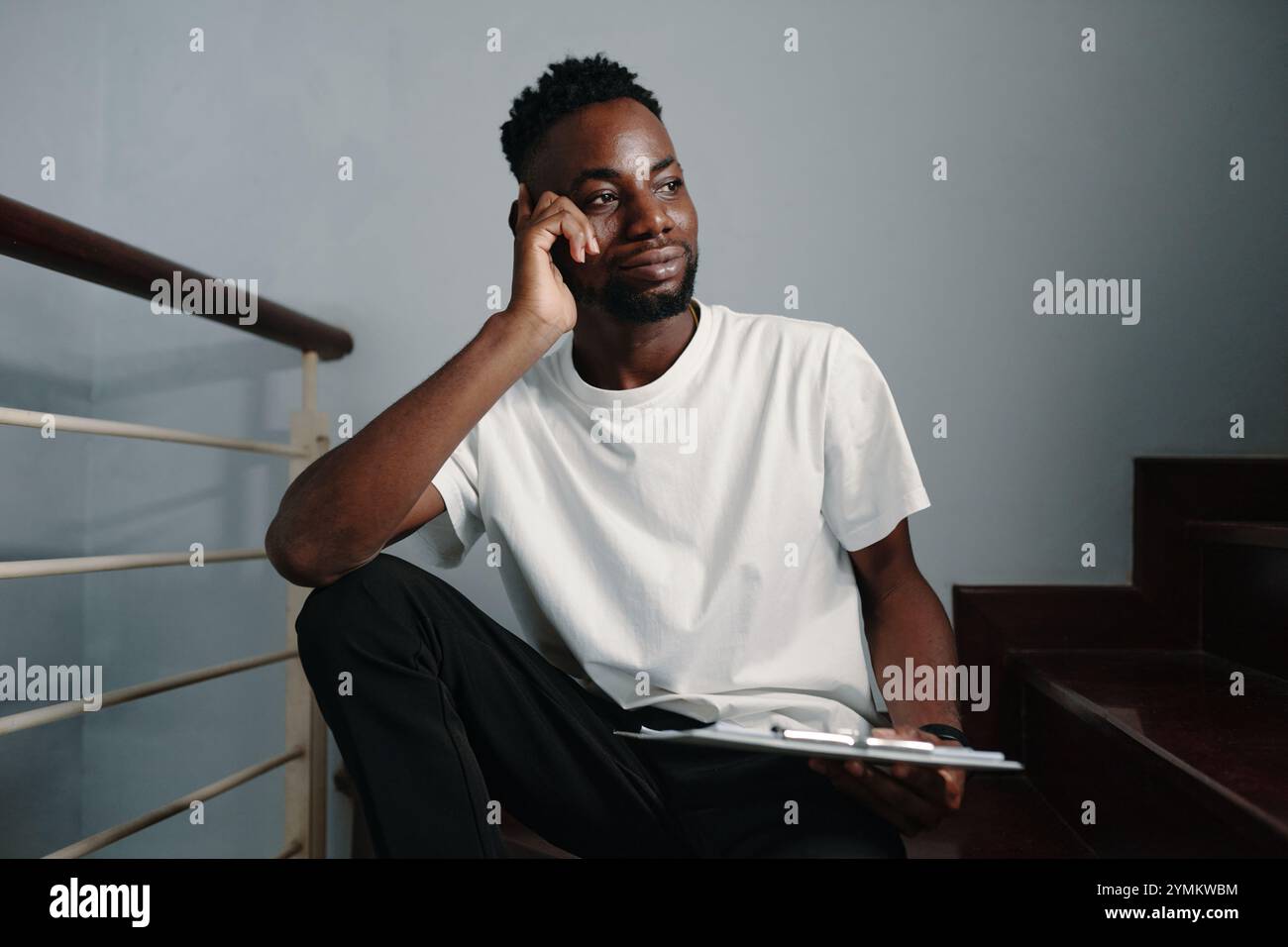 African American Man Sitting Thoughtfully Holding Tablet Stock Photo