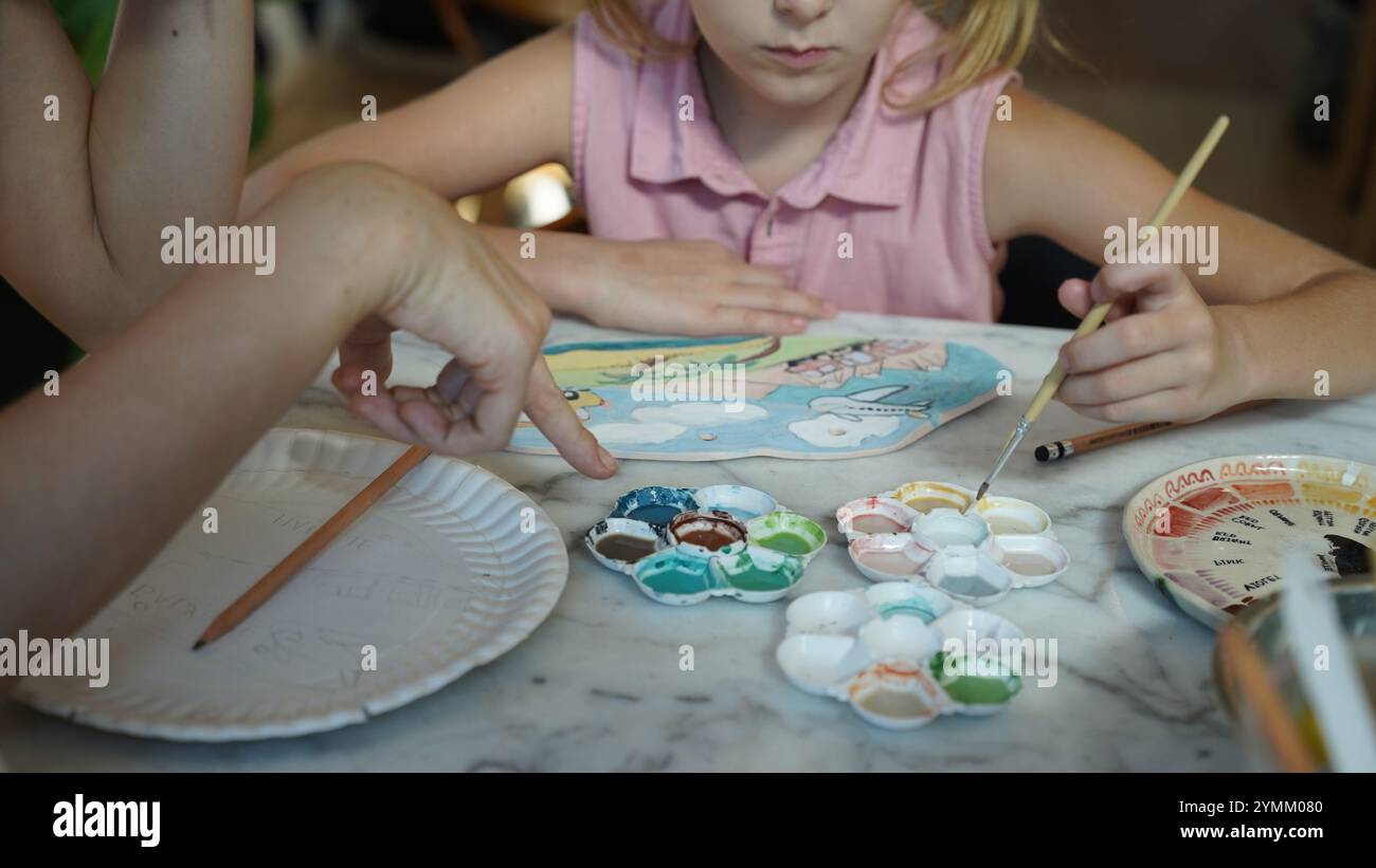 A young mother and her daughter enjoy a creative art session at home ...