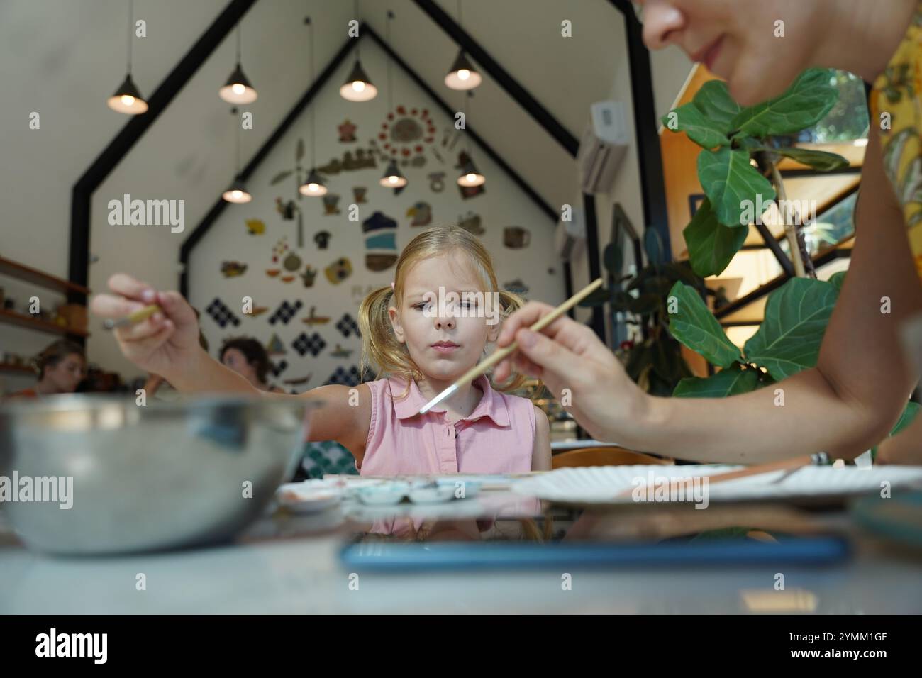 A young mother and her daughter enjoy a creative art session at home ...