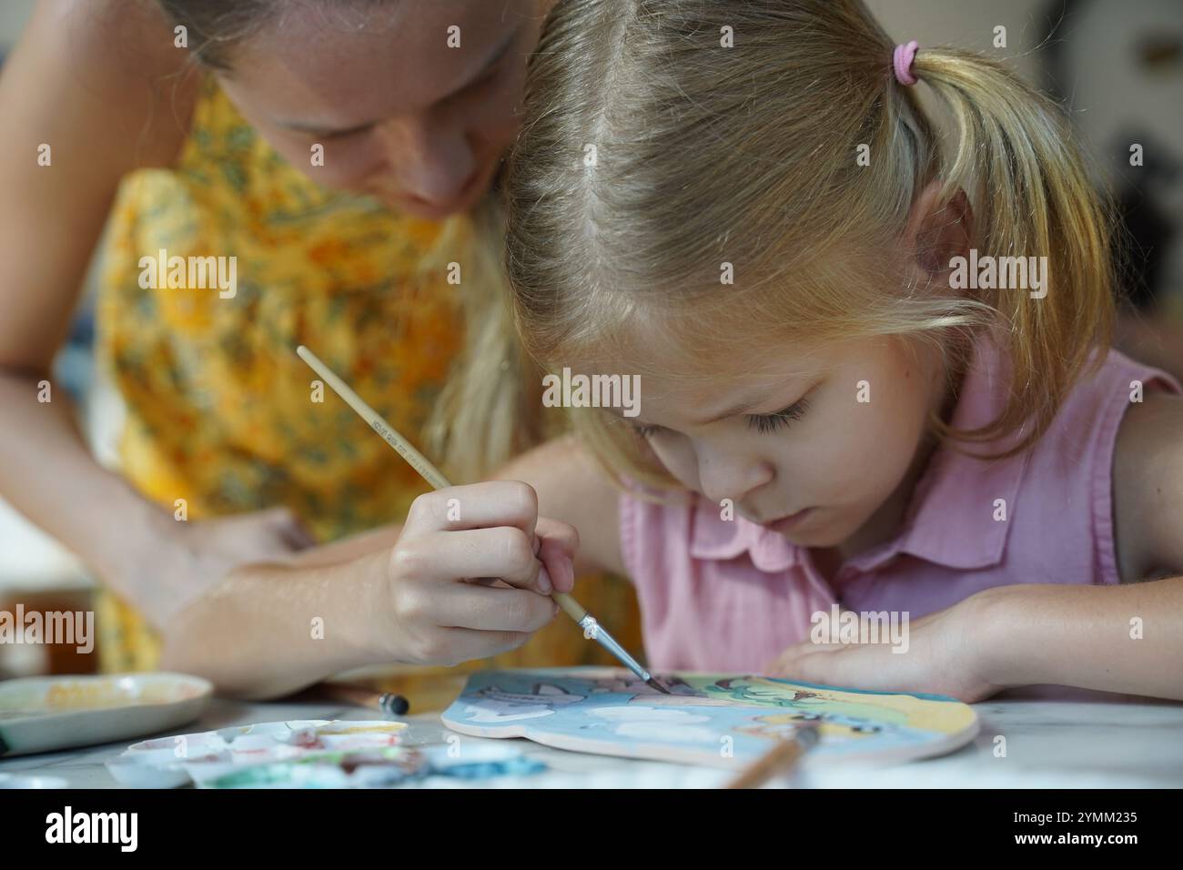 A young mother and her daughter enjoy a creative art session at home ...