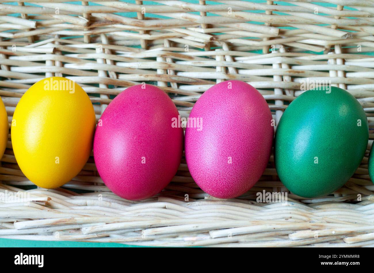 close up of four easter eggs colored in a straw basket Stock Photo