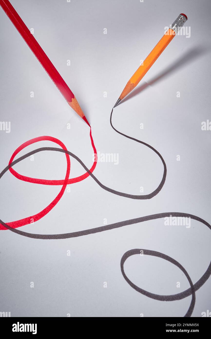 Red and black pencils drawing swirling lines Stock Photo