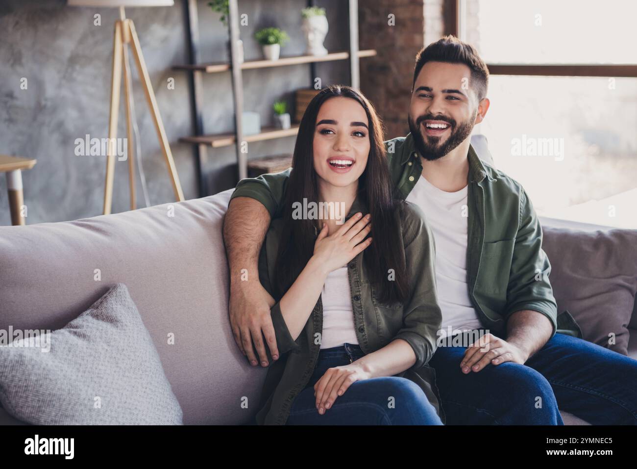 Photo of positive married people wife husband sitting on couch together