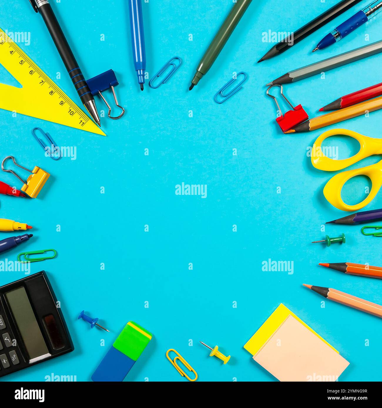 Various colorful markers and stationery items are scattered on a blue surface, showcasing vibrant tools for creativity and organization. Stock Photo