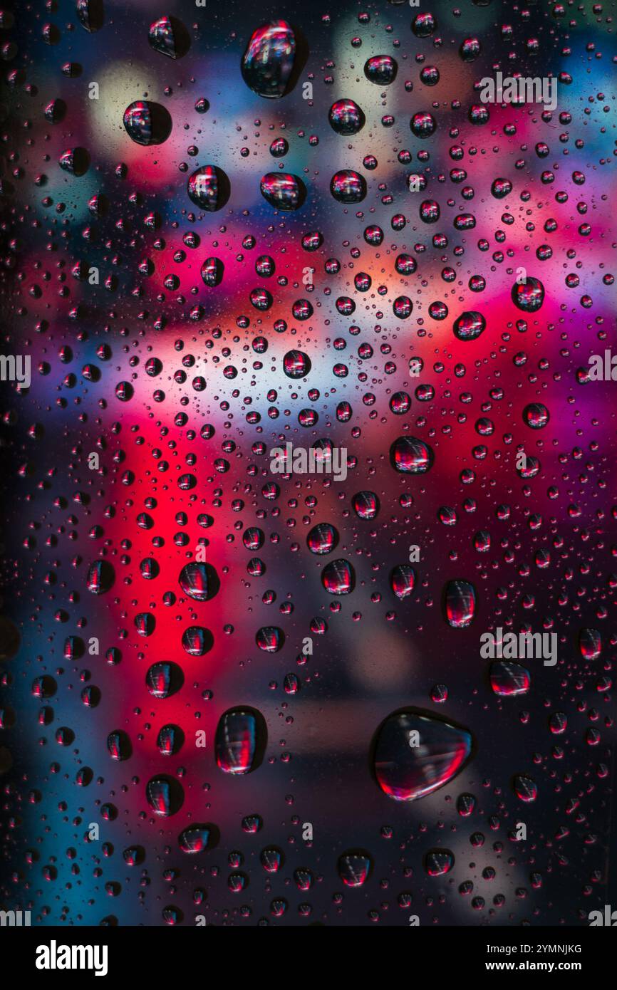 City view through a window on a rainy night,Rain drops on window with road light bokeh Stock Photo