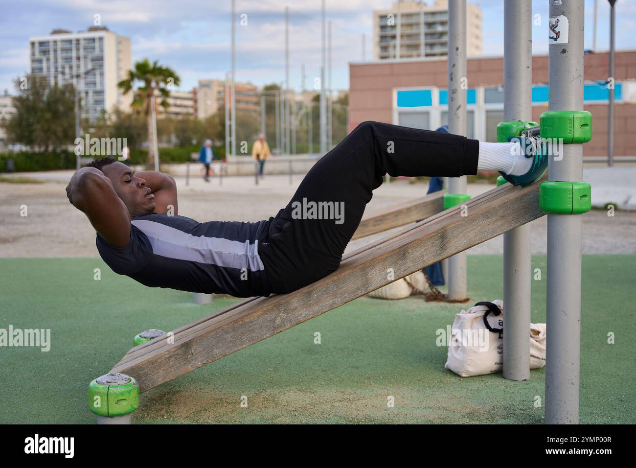Young black man doing calisthenics sit-ups in an outdoor gym Stock ...
