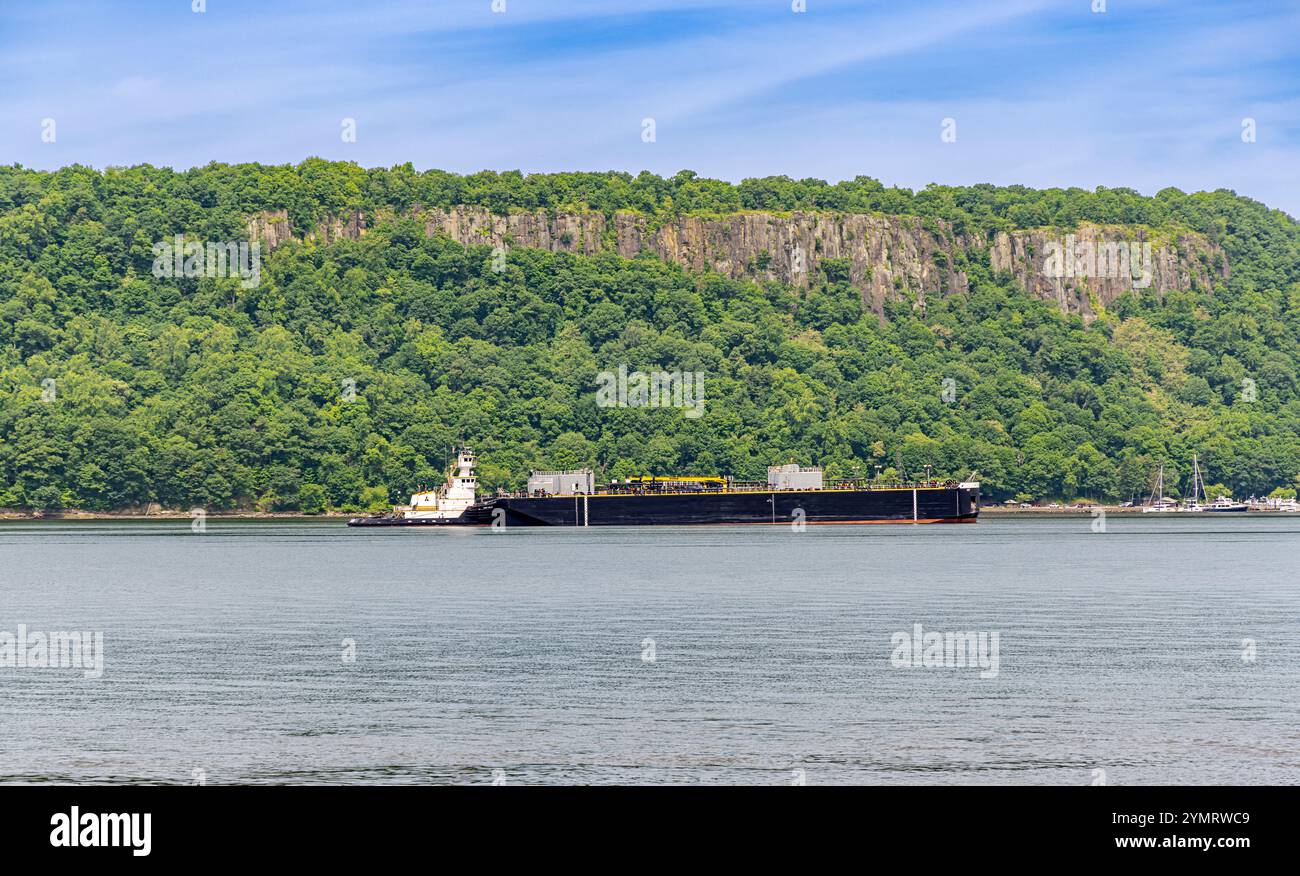 river tug boat pushing a large barge on the hudson river with the palisades in the background Stock Photo