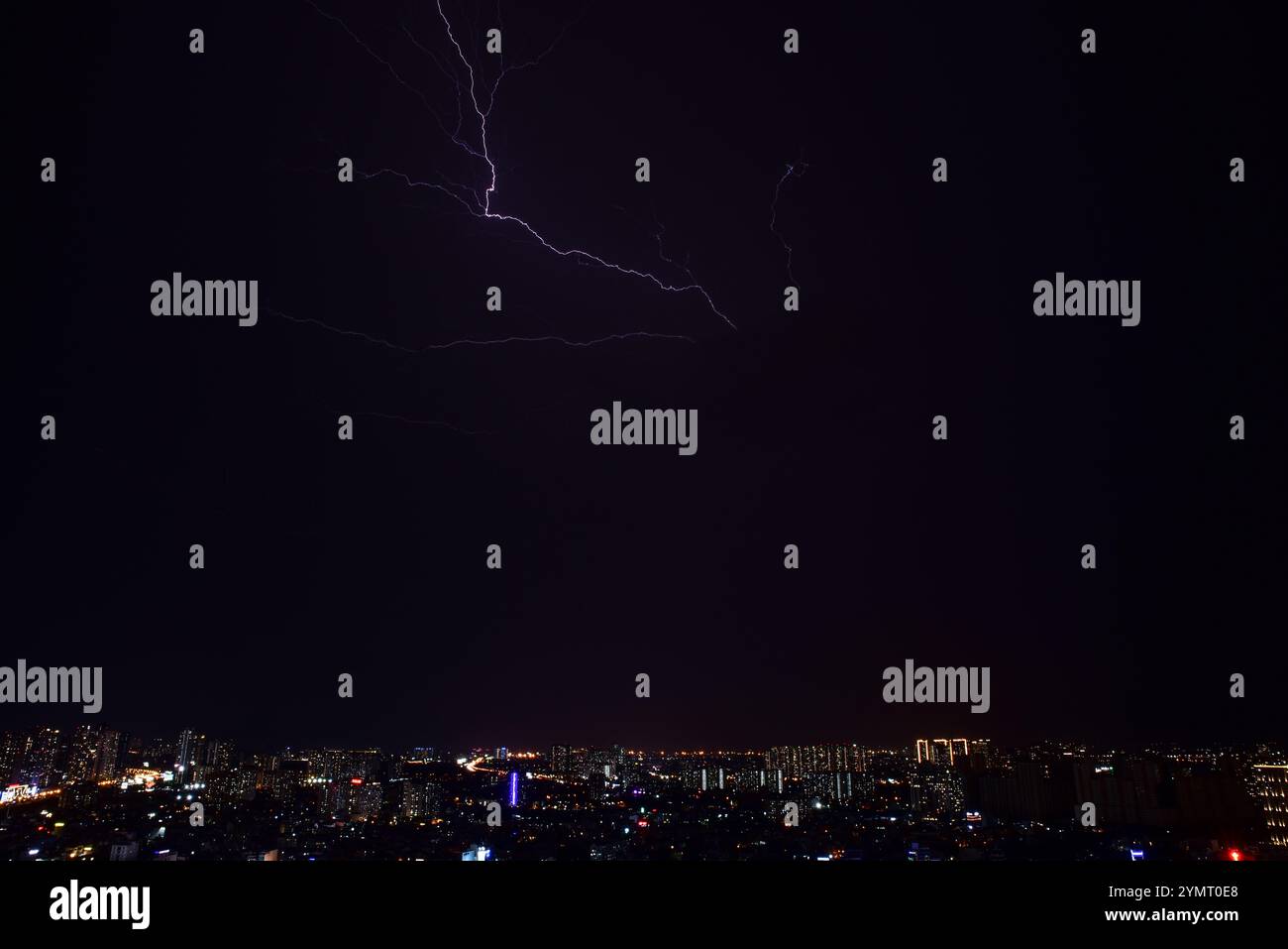The city skyline is illuminated by a bright lightning bolt that streaks ...