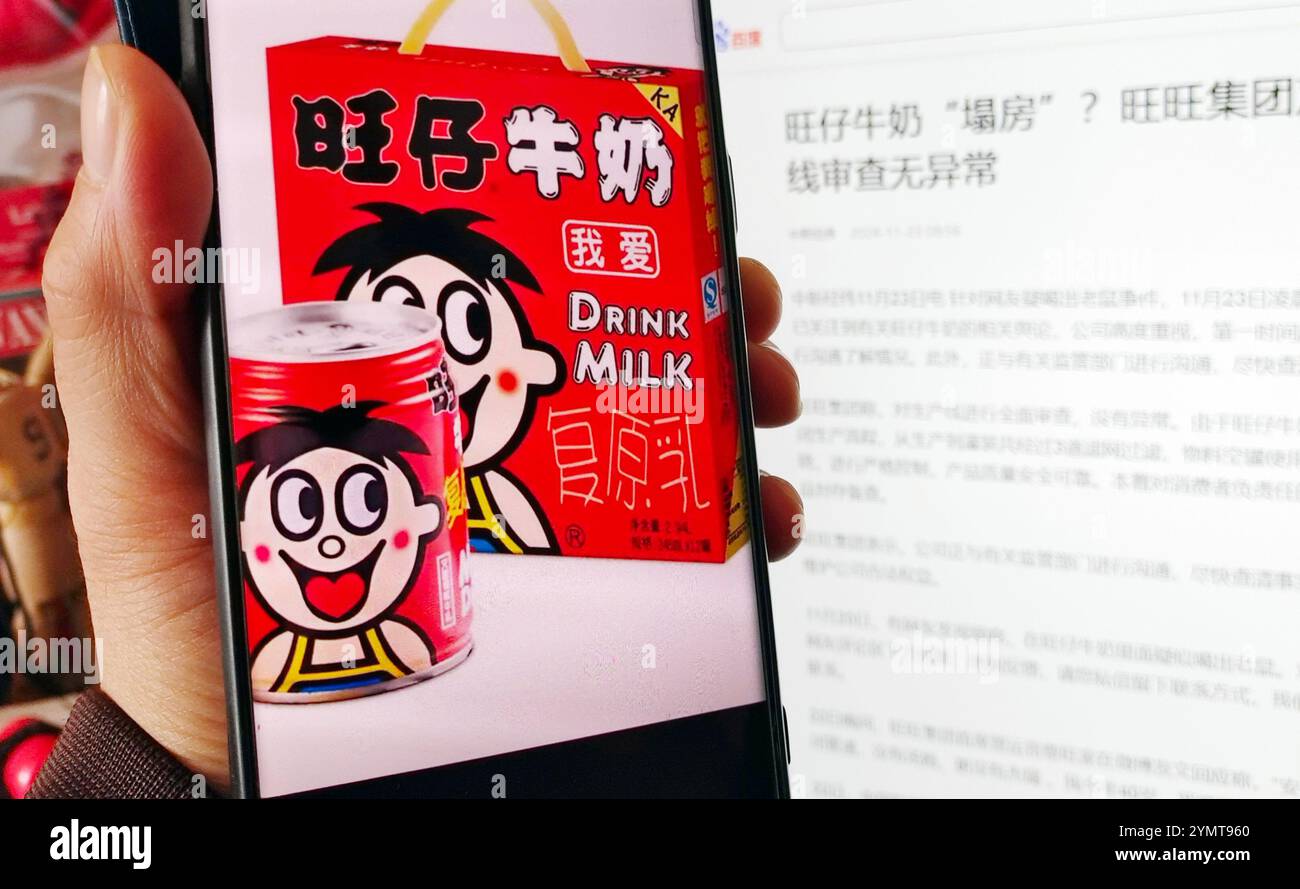 A consumer shows a screenshot of Wangzai milk e-commerce products and a news report of Want Want Group's response, November 23, 2024, Shanghai, China. Stock Photo