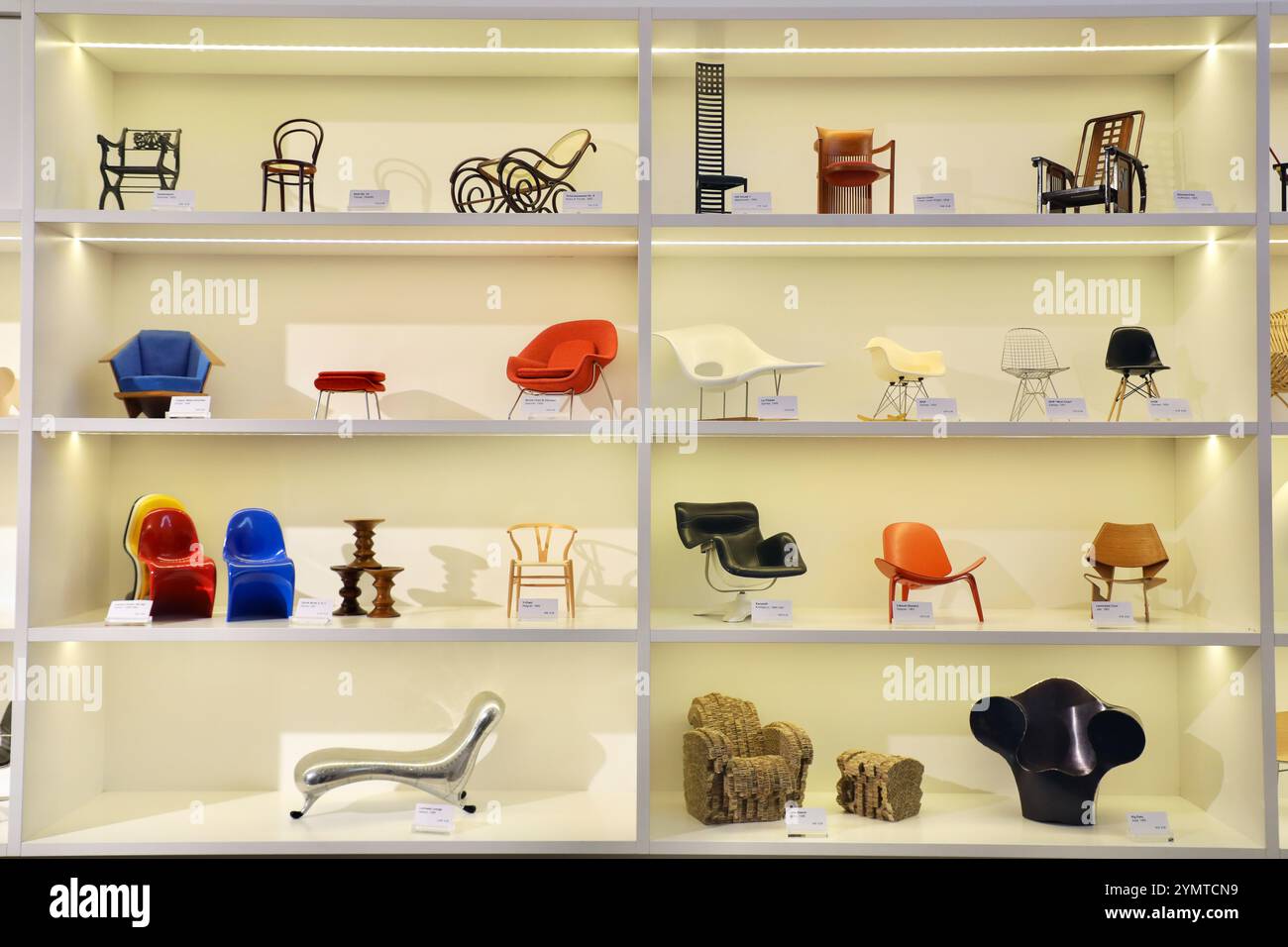 Miniatures of designer chairs on display in the store window at the Vitra Museum in Weil am Rhein, Germany, trace the history of design.From left to right on the top shelf: Gartenstuhl by Karl Friedrich Schinkel, Stuhl No. 14 by Michael Thonet & Sons, Schaukelsessel No. 9 by J. & J. Kohn, Hill House 1 by Charles Rennie Mackintosh, Barrel Chair by Frank Lloyd Wright and Sitzmaschine by Josef Hoffmann. On the second highest shelf : Taliesin West Chair by Frank Lloyd Wright, Womb Chair & Ottoman by Eero Saarinen, La Chaise, RAR and DSW by Charles & Ray Eames.  On the second lowest shelf : Panton Stock Photo