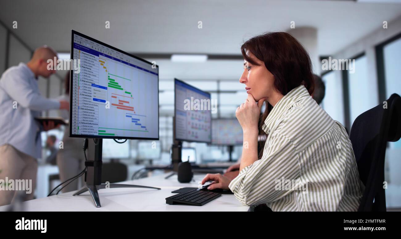 Businesspeople Analyzing Gantt Chart And Calendar On Computer In Office Stock Photo