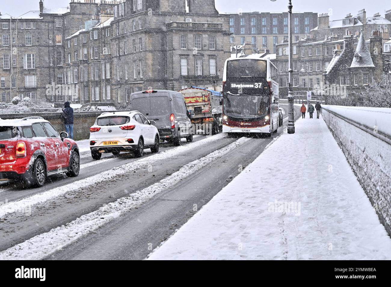 Edinburgh, Scotland, UK. 23rd Nov 2024. Heavy snow in the West End part of the city disrupts cars and pedestrians temporarily. Snow persists in the West End longer than anticipated. Queueing Traffic on the Dean Bridge.  Credit: Craig Brown/Alamy Live News Stock Photo