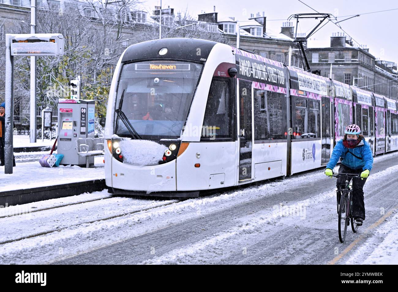 Edinburgh, Scotland, UK. 23rd Nov 2024. Heavy snow in the West End part of the city disrupts public transport and pedestrians temporarily. Snow persists in the West End longer than anticipated.  Tram and cyclist at the West End tram stop. Credit: Craig Brown/Alamy Live News Stock Photo