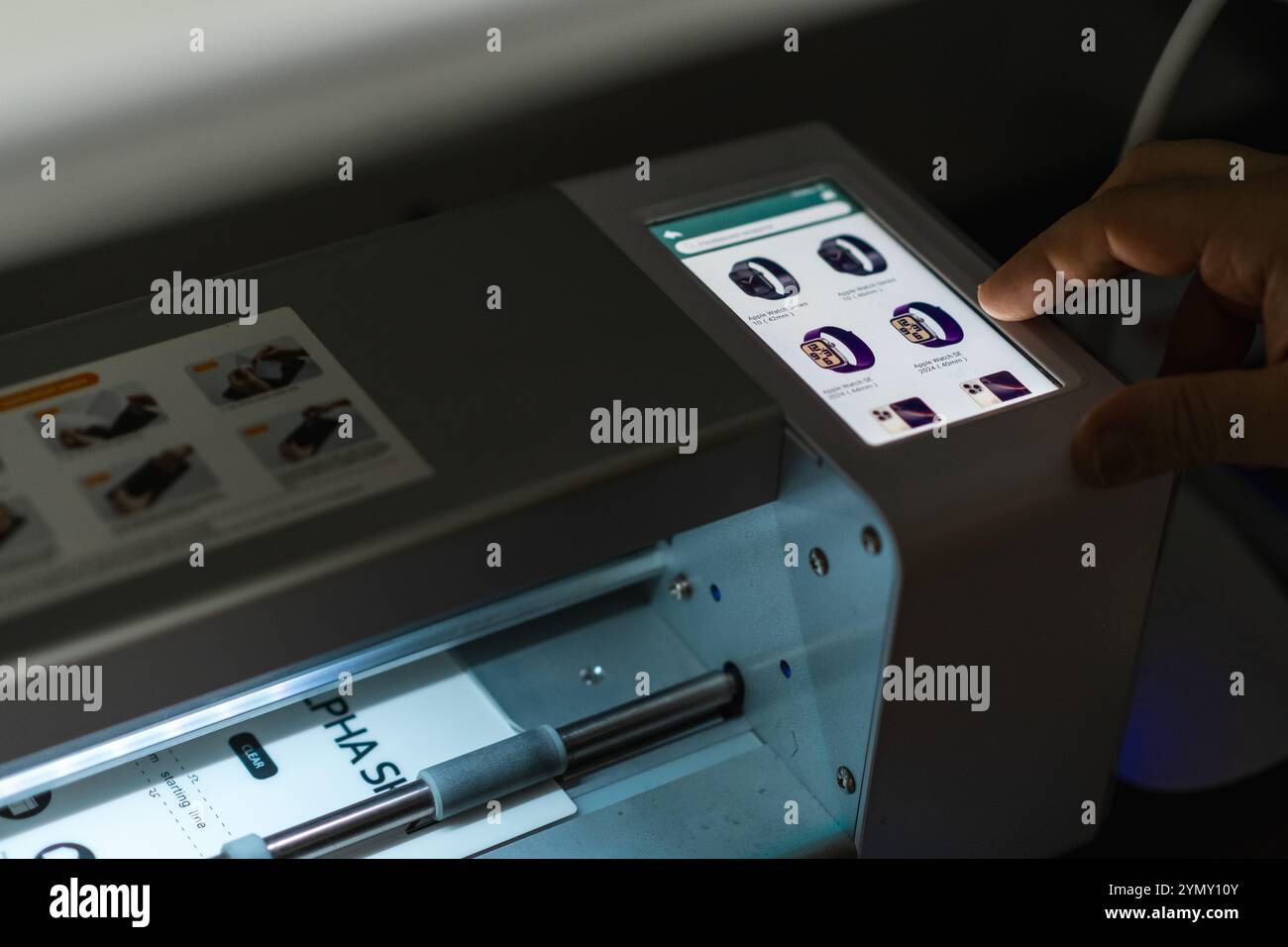 User interacts with a precise plotter for cutting hydrogel film in a modern workspace during the day Stock Photo