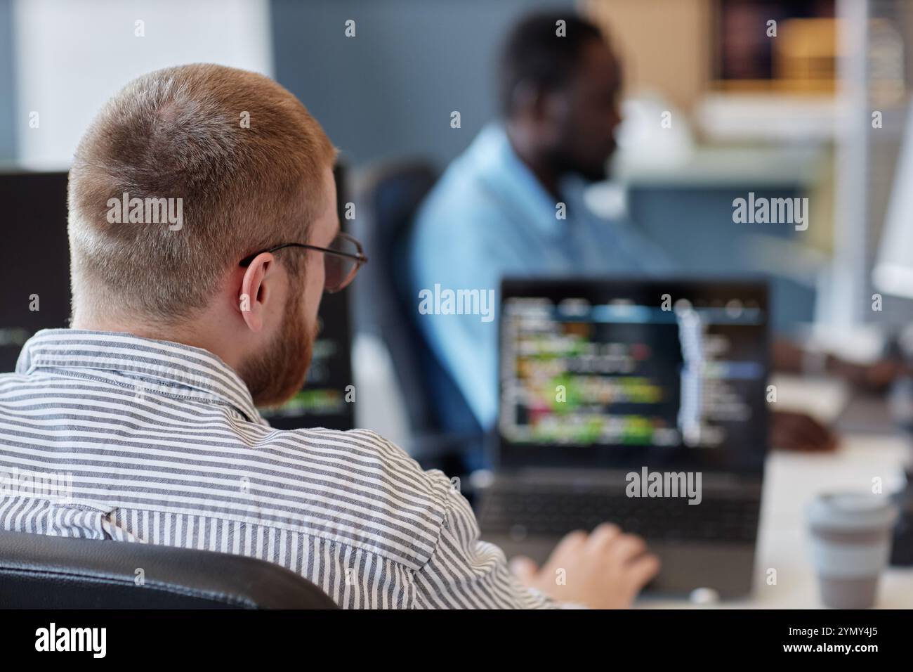 Portrait of developer concentrating on computer screen while coding in collaborative office space Stock Photo