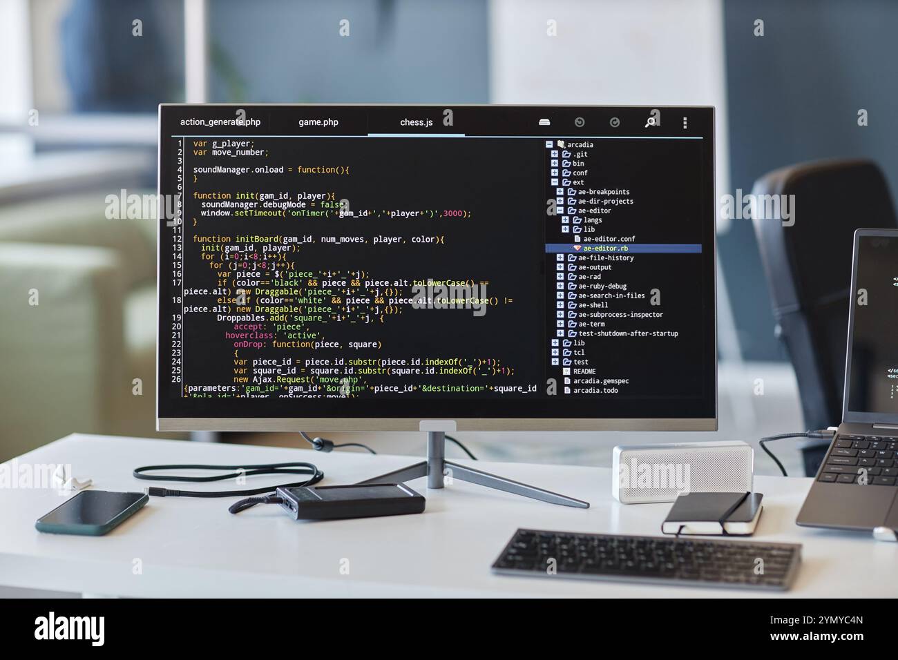Workspace with multiple electronics, including computer monitors, keyboards, and other devices used for developing software and managing code displayi Stock Photo