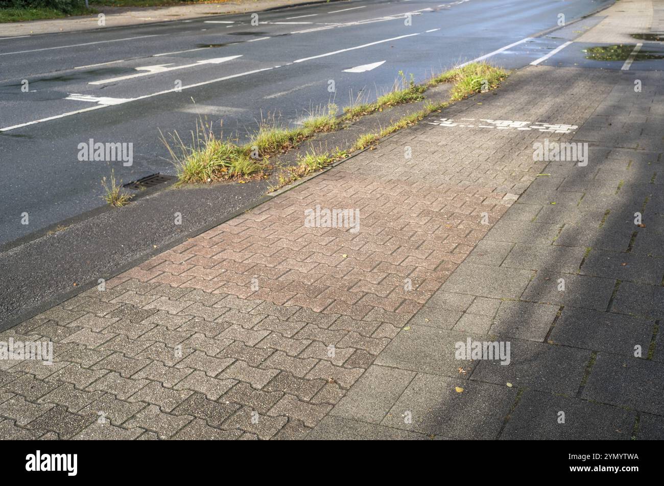 Wet road with cycle path and sidewalk, poorly maintained Stock Photo ...