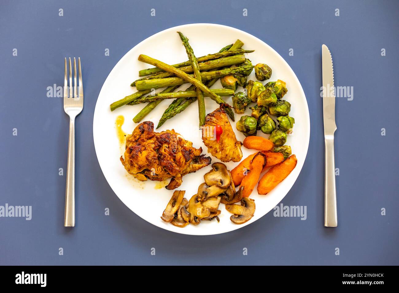 Real, strong, healthy, nutritious food, grilled chicken, pimenta biquinho, asparagus, mushrooms, Brussels sprouts and carrots. Stock Photo