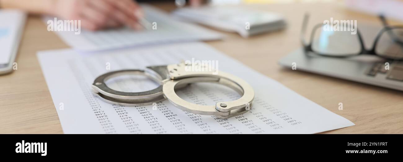 Handcuffs on investigation paper while worker making counts Stock Photo