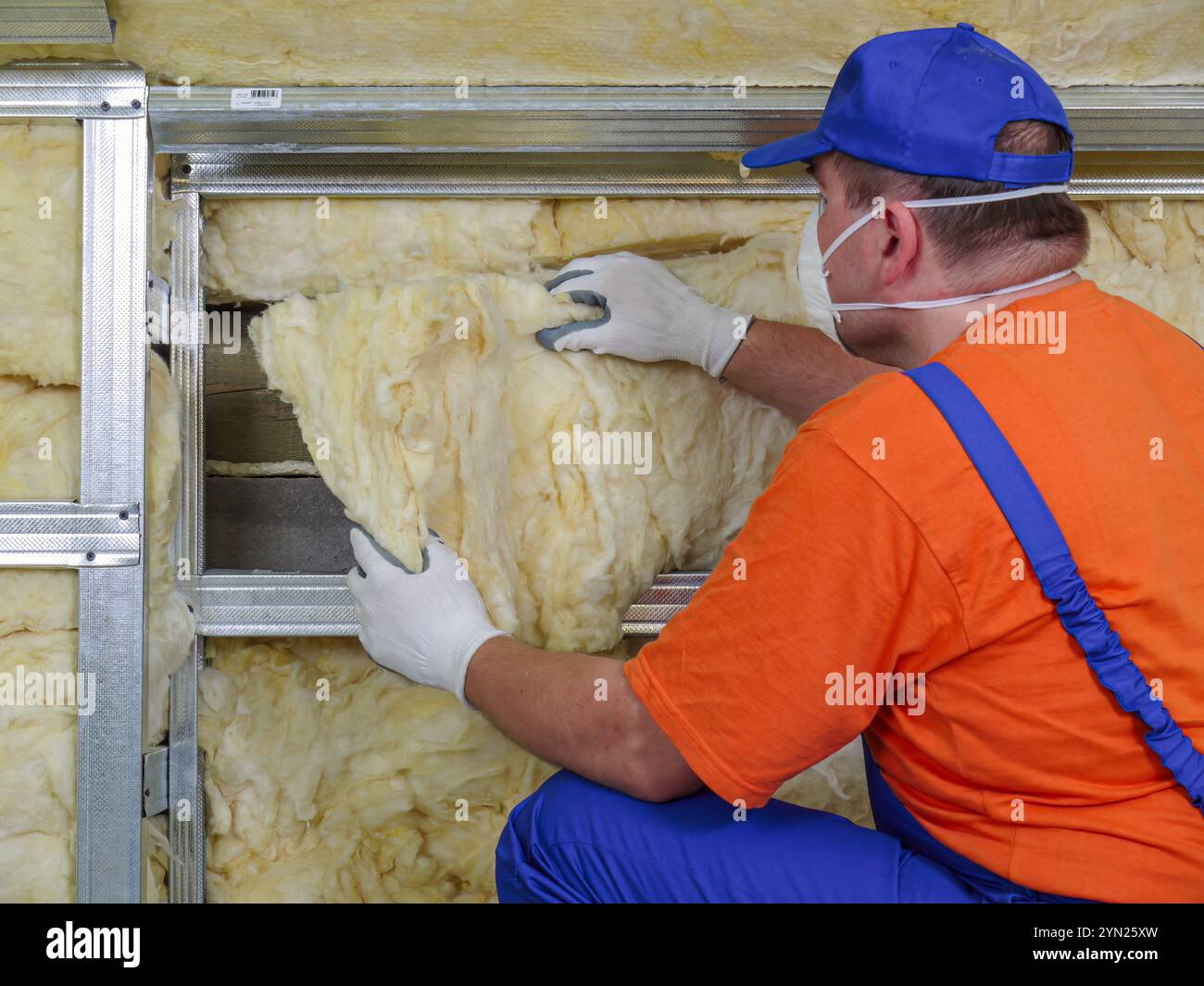 Construction worker thermally insulating house attic with mineral wool ...