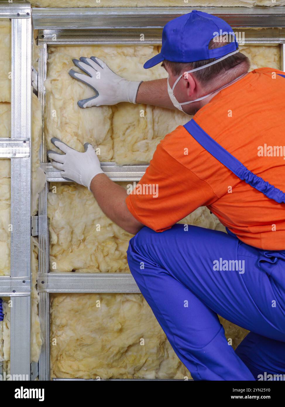 Construction worker thermally insulating house attic with mineral wool ...
