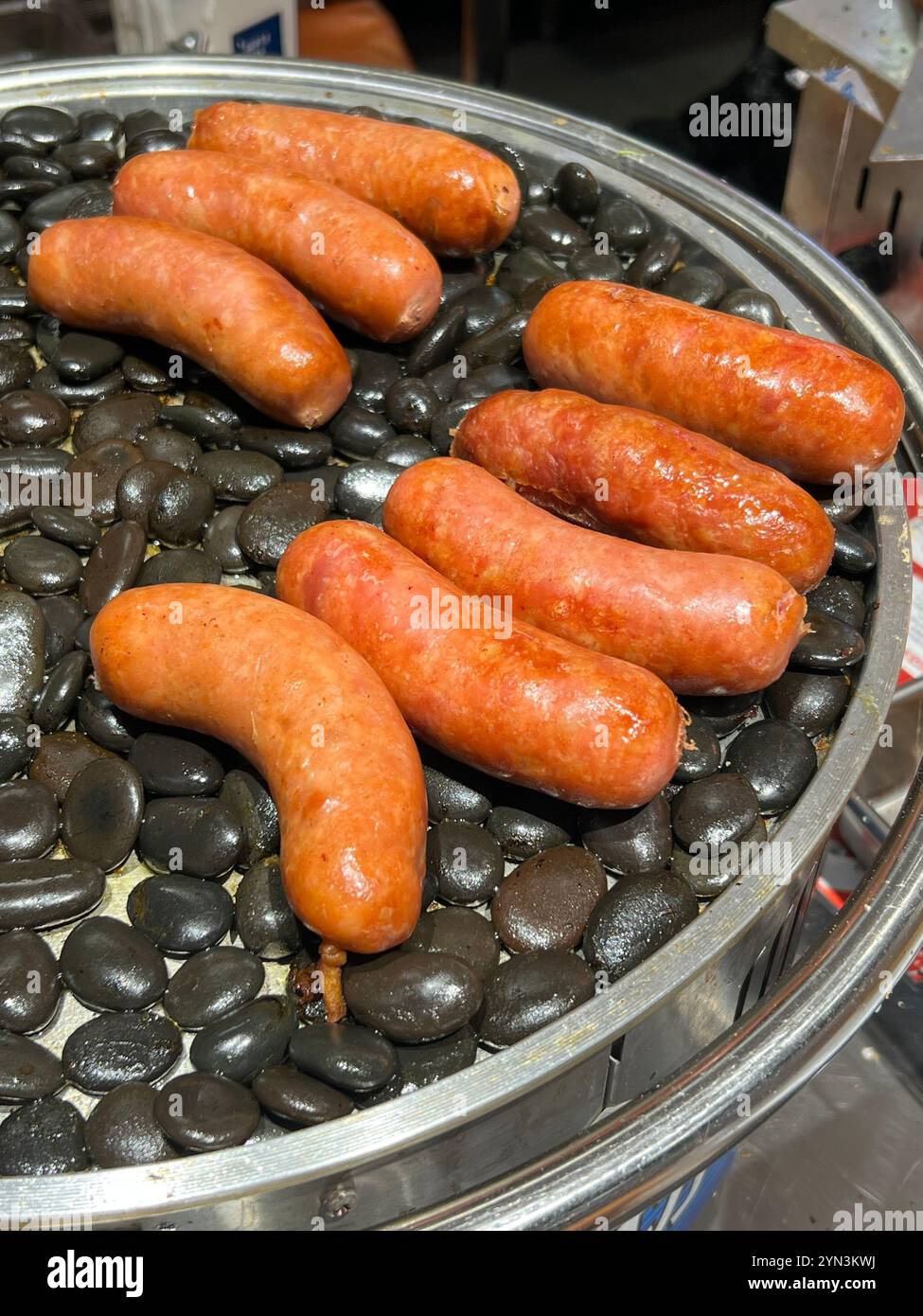 Grilled thick flavour minced pork sausage cooked on black hot stones pebbles to keep it warm. Scarlett supermarket. China Chinese brand. Singapore. - Smartphone Captured Stock Image