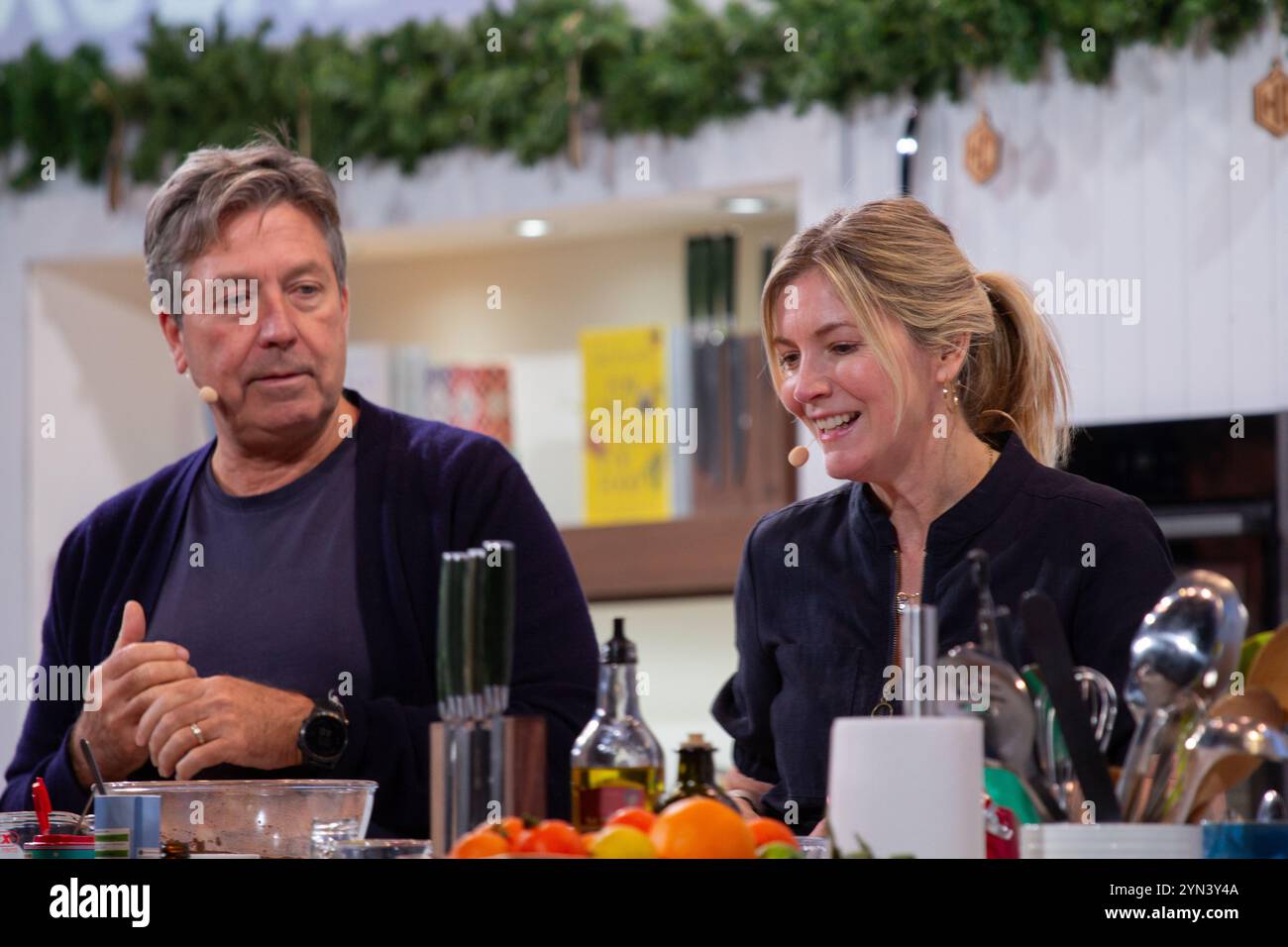 Chef John Torode and his wife Lisa Faulkner on the Big Kitchen Stage at the Winter Goodfood Show NEC cooking in front of excited crowd  of food lovers Stock Photo