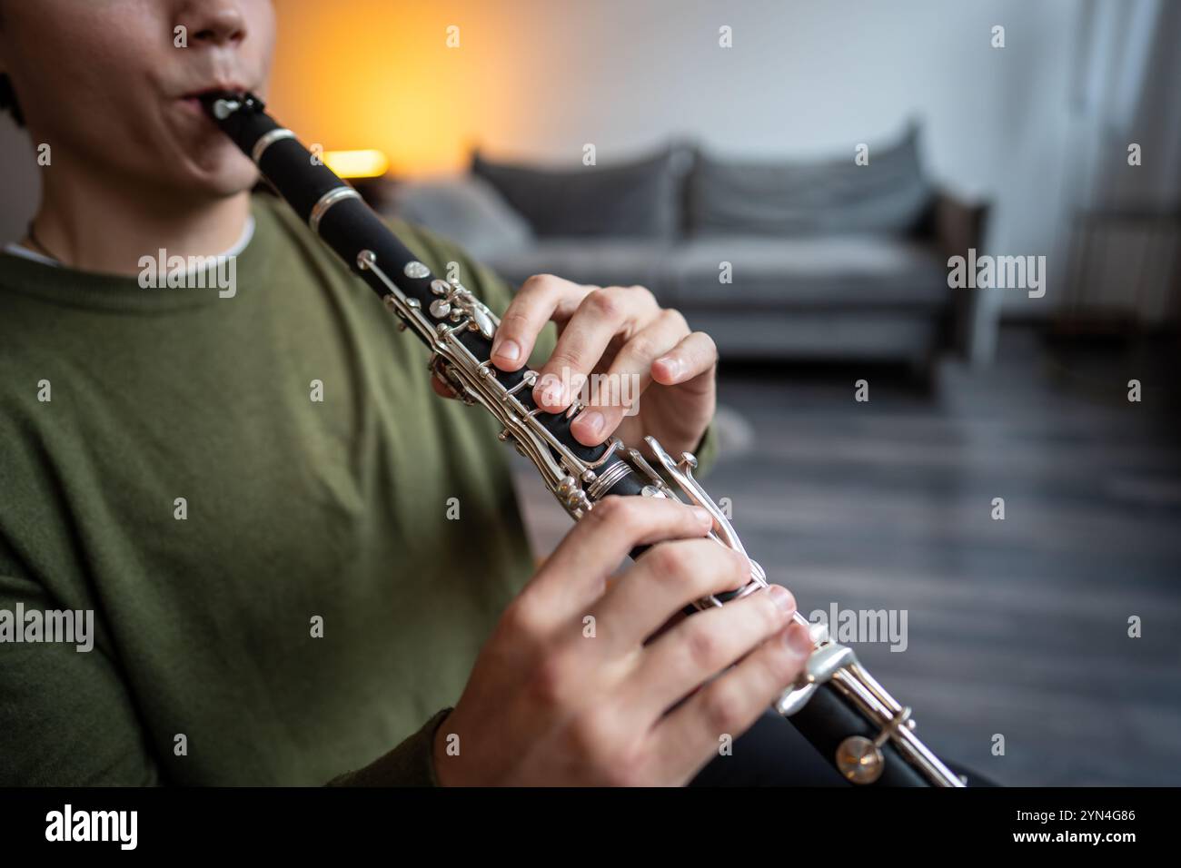 Clarinet player. Clarinetist hands playing flute woodwind music instrument at home, closeup view Stock Photo