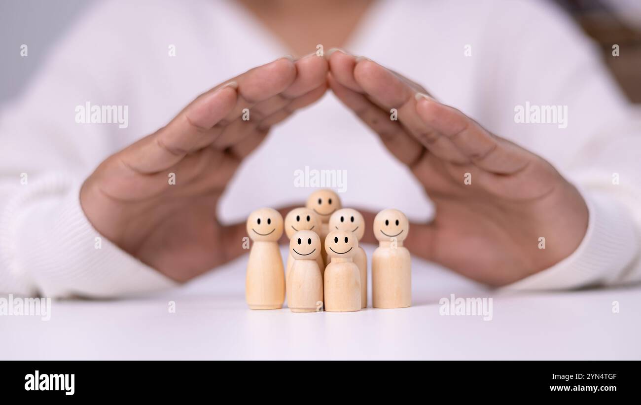 Hand of a person laying down protection a wooden dolls to show represents the protection of family safety, Insurance management planning, Health care Stock Photo