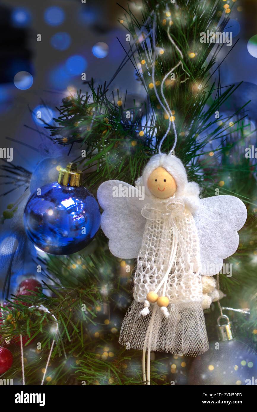White hand-made angel decorates Christmas tree. Stock Photo