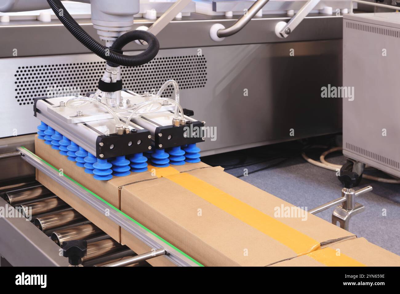 A cardboard box is lifted from a metal conveyor by an automatic ...