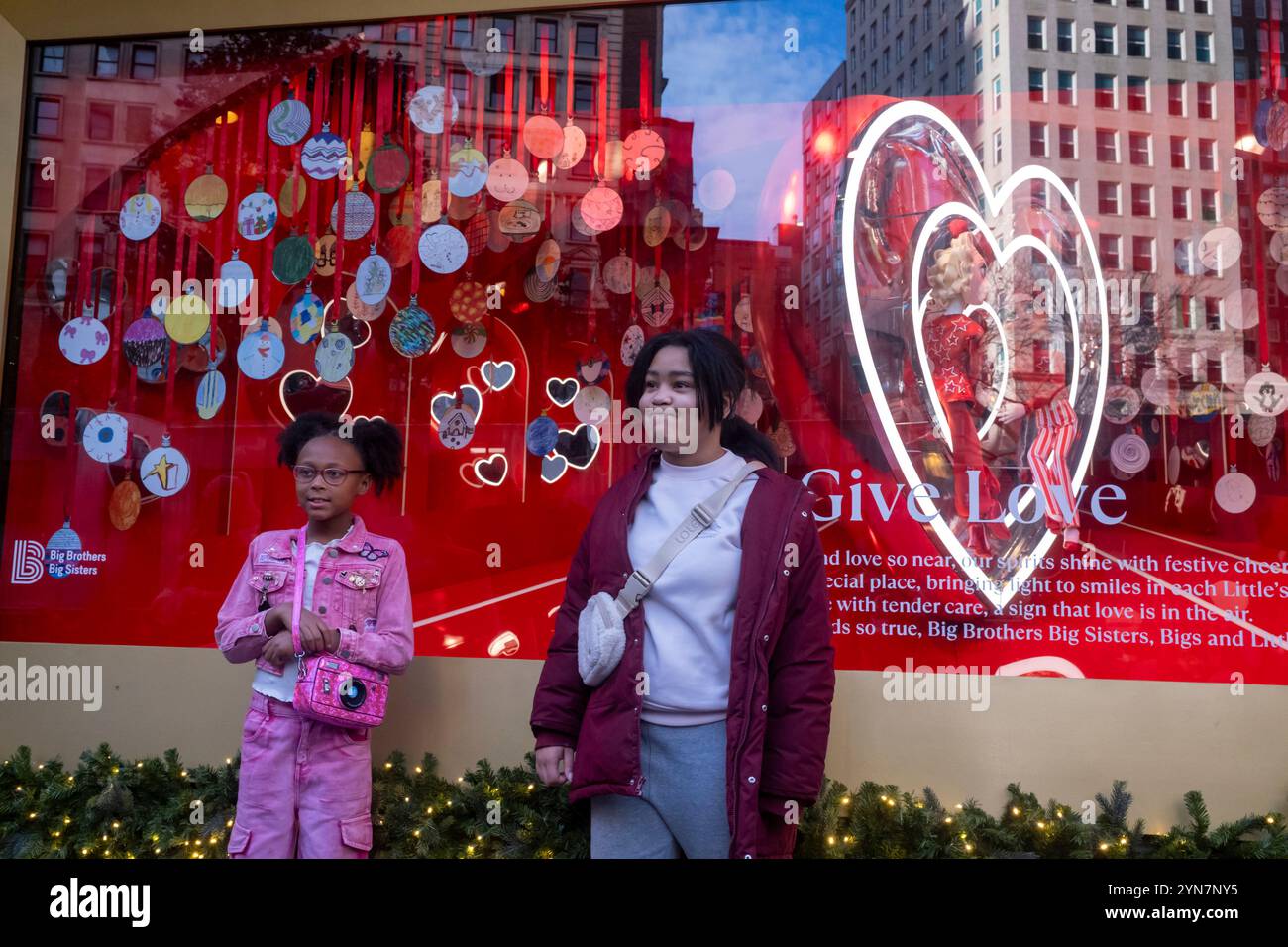 New York, United States. 24th Nov, 2024. NEW YORK, NEW YORK - NOVEMBER 24: Girls pose in-front of the Macy's holiday window displays at the Macy's Herald Square flagship store on 34th Street in Midtown Manhattan on November 24, 2024 in New York City. Credit: Ron Adar/Alamy Live News Stock Photo