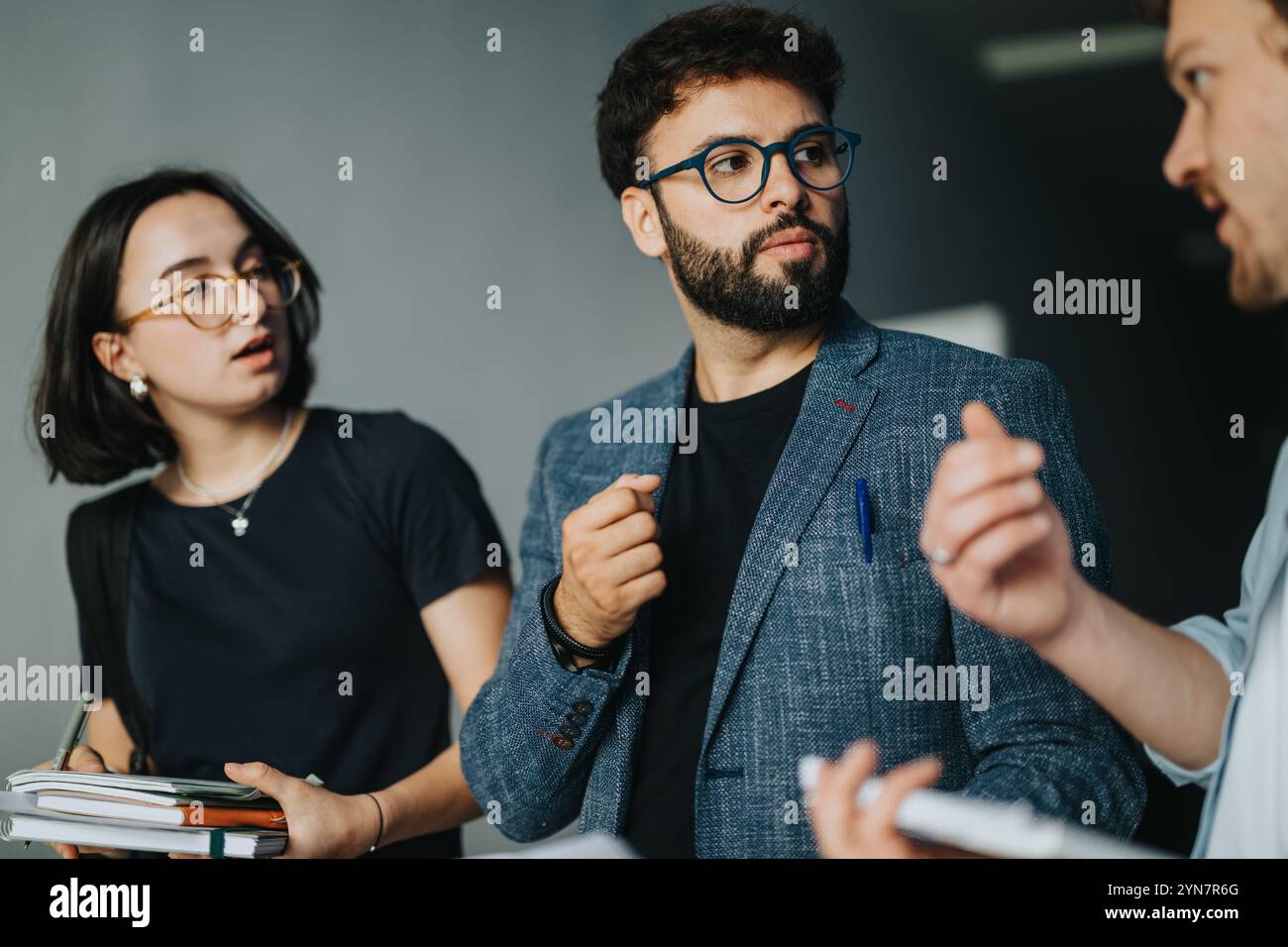Engaged students conversing with professor in university corridor Stock Photo