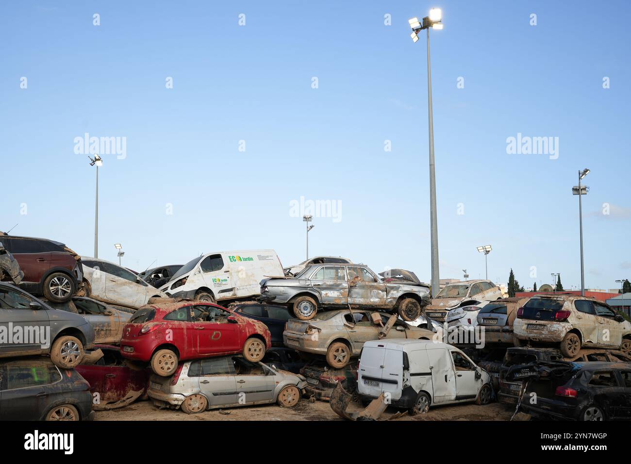 Benetússer, Spain - November 24, 2024. Damaged cars after DANA flooding are stored and piled up in the football field and installations of Benetússer sport center (polideportivo del Benetússer) and still there almost a month after the disaster that swept through eastern and southern areas of Spain. Thousands of people lost their vehicle and are seen looking for them in the cars' cemeteries while other vehicles are half buried in the river bed of Poyo ravine (Barranco del Poyo). Car dealerships have waiting lists due to the high number of requests. Credit: Roberto Arosio/Alamy Live News Stock Photo