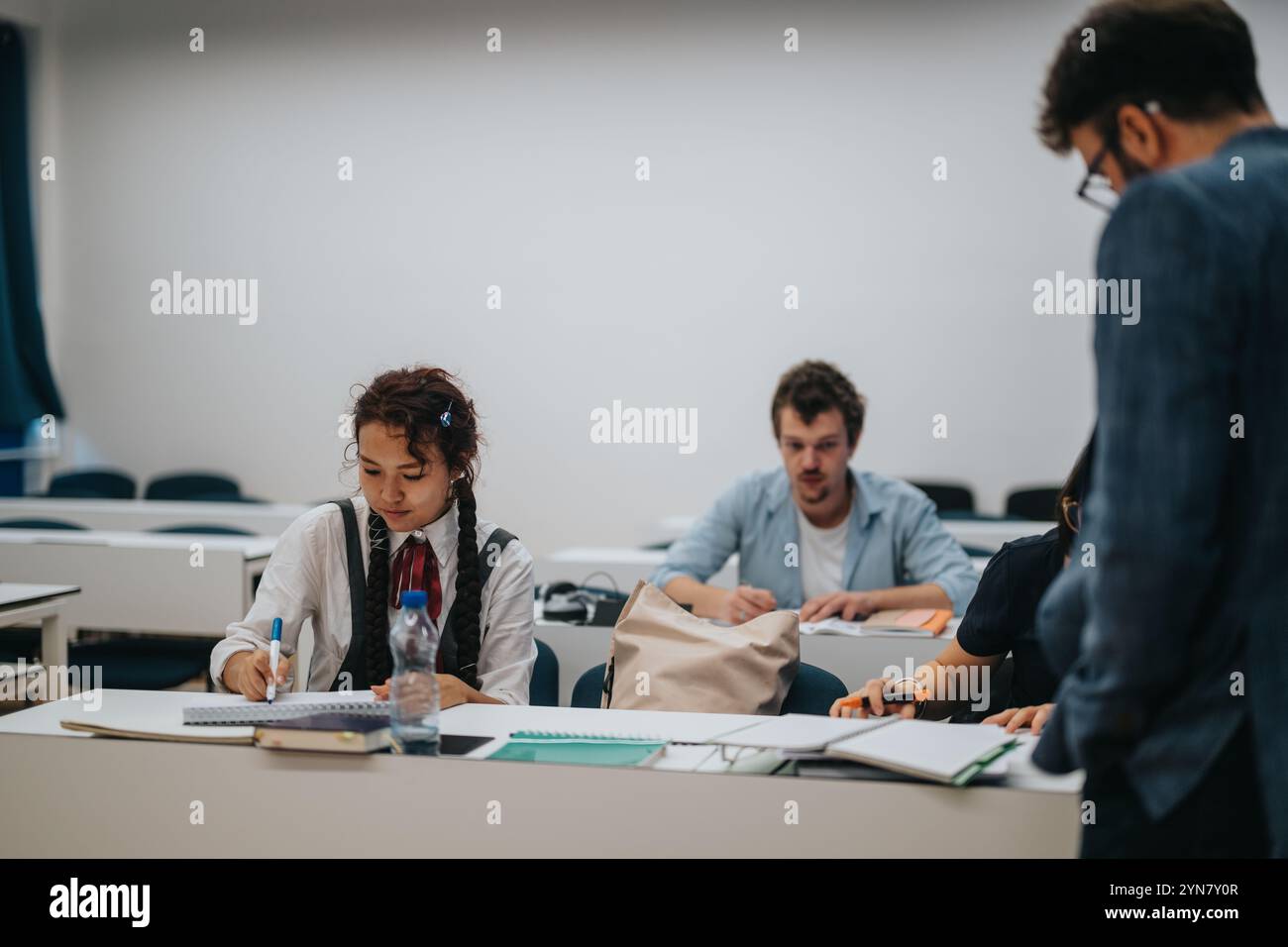 Students engaged in learning with professor assisting during class Stock Photo
