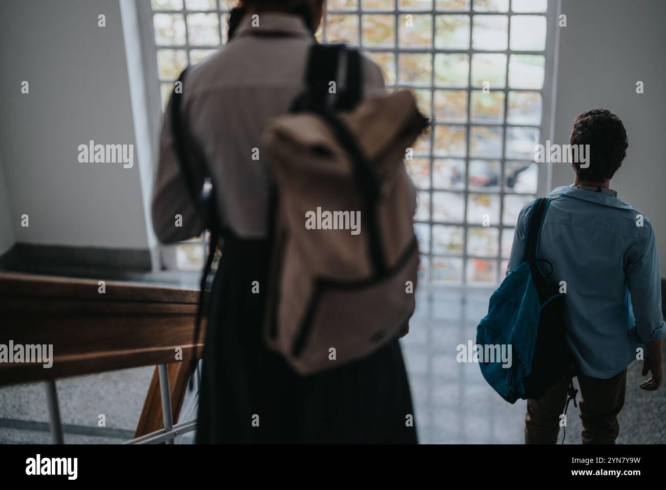 Two students walking down a school staircase with backpacks Stock Photo