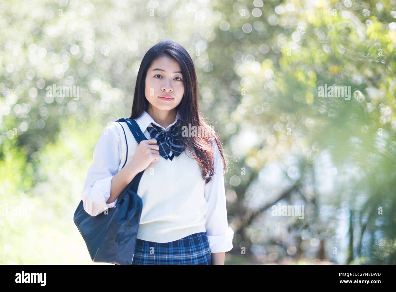 Schoolgirl in school uniform standing in green Stock Photo - Alamy