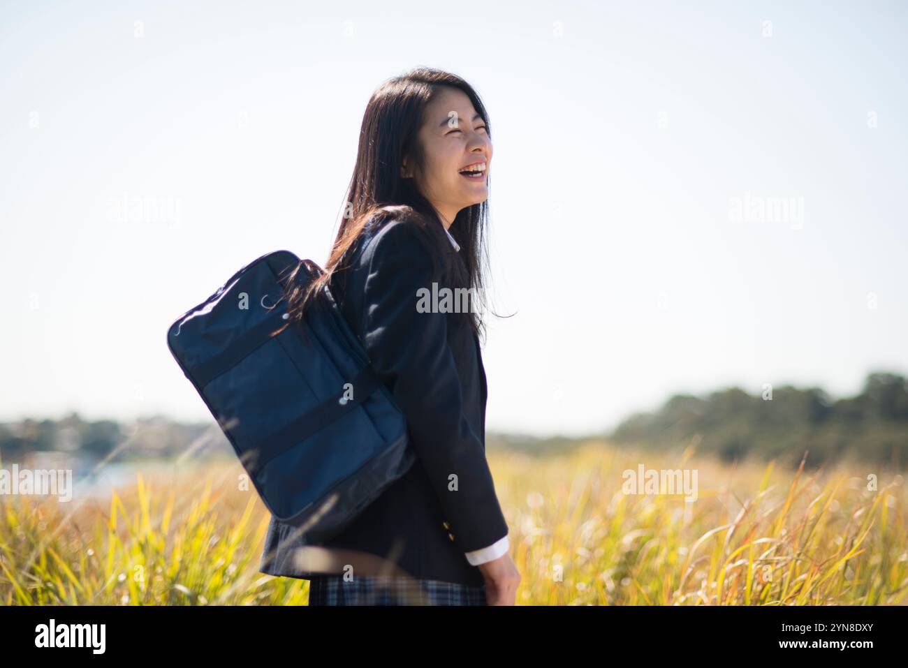 High school girl in uniform standing in grassland laughing Stock Photo ...
