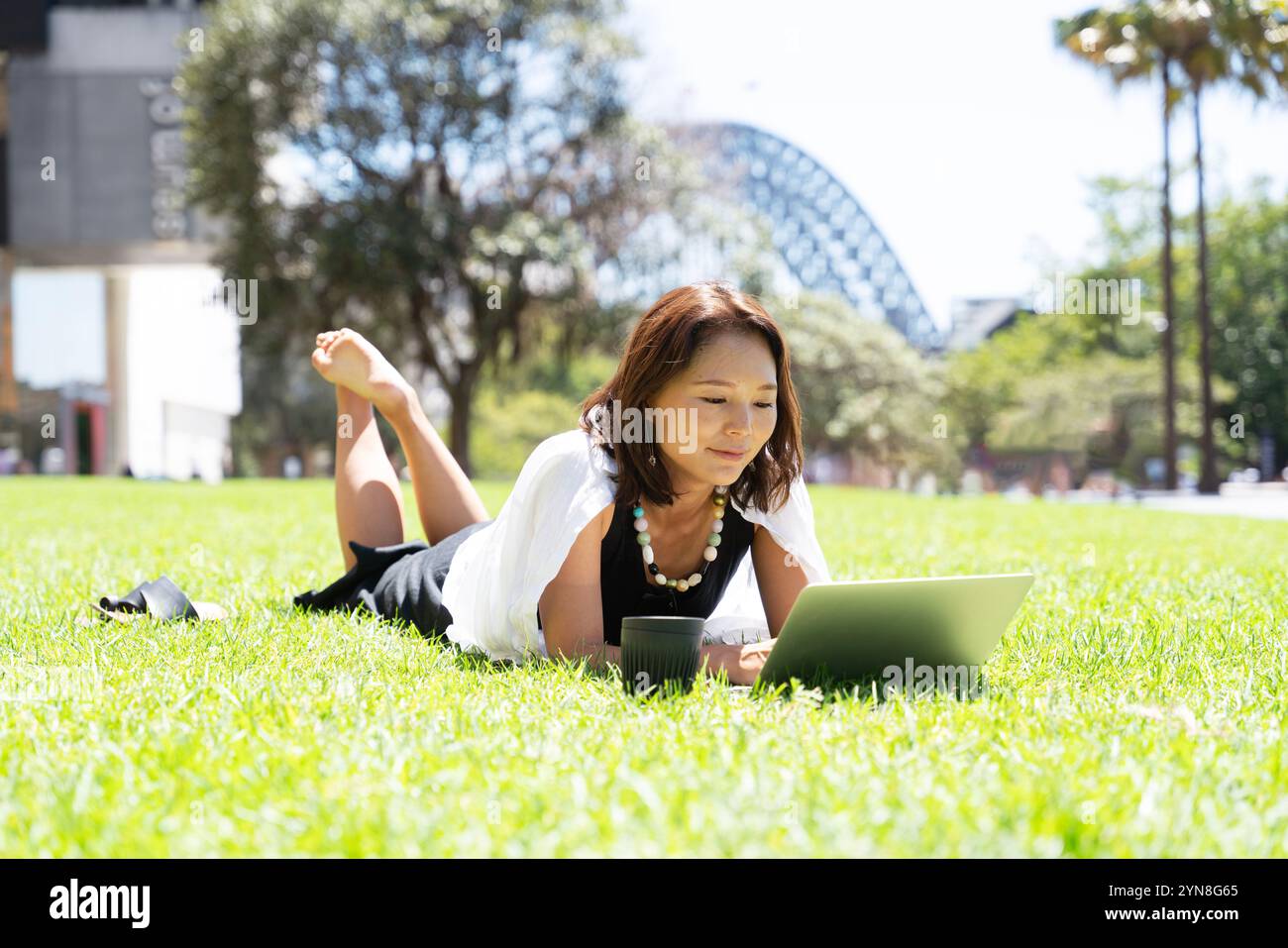 Woman lying on lawn with computer spread out Stock Photo - Alamy