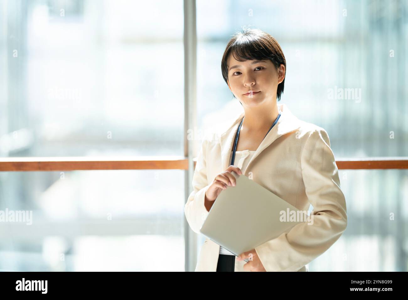Woman standing inside a building holding a computer Stock Photo